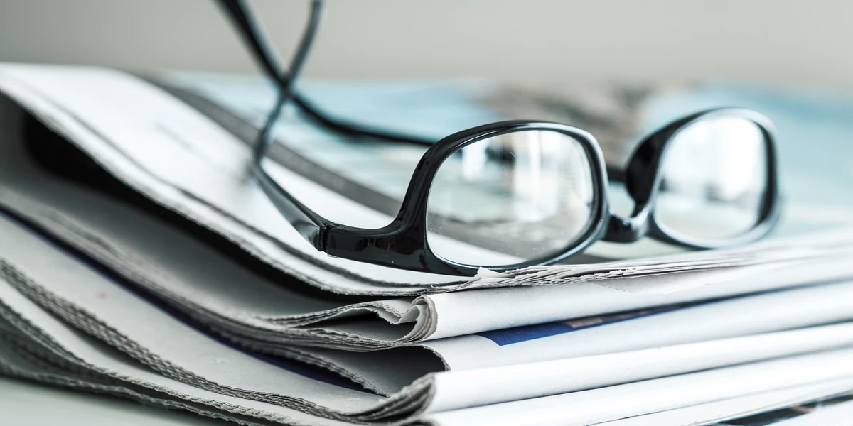 Stack of newspapers with reading glasses